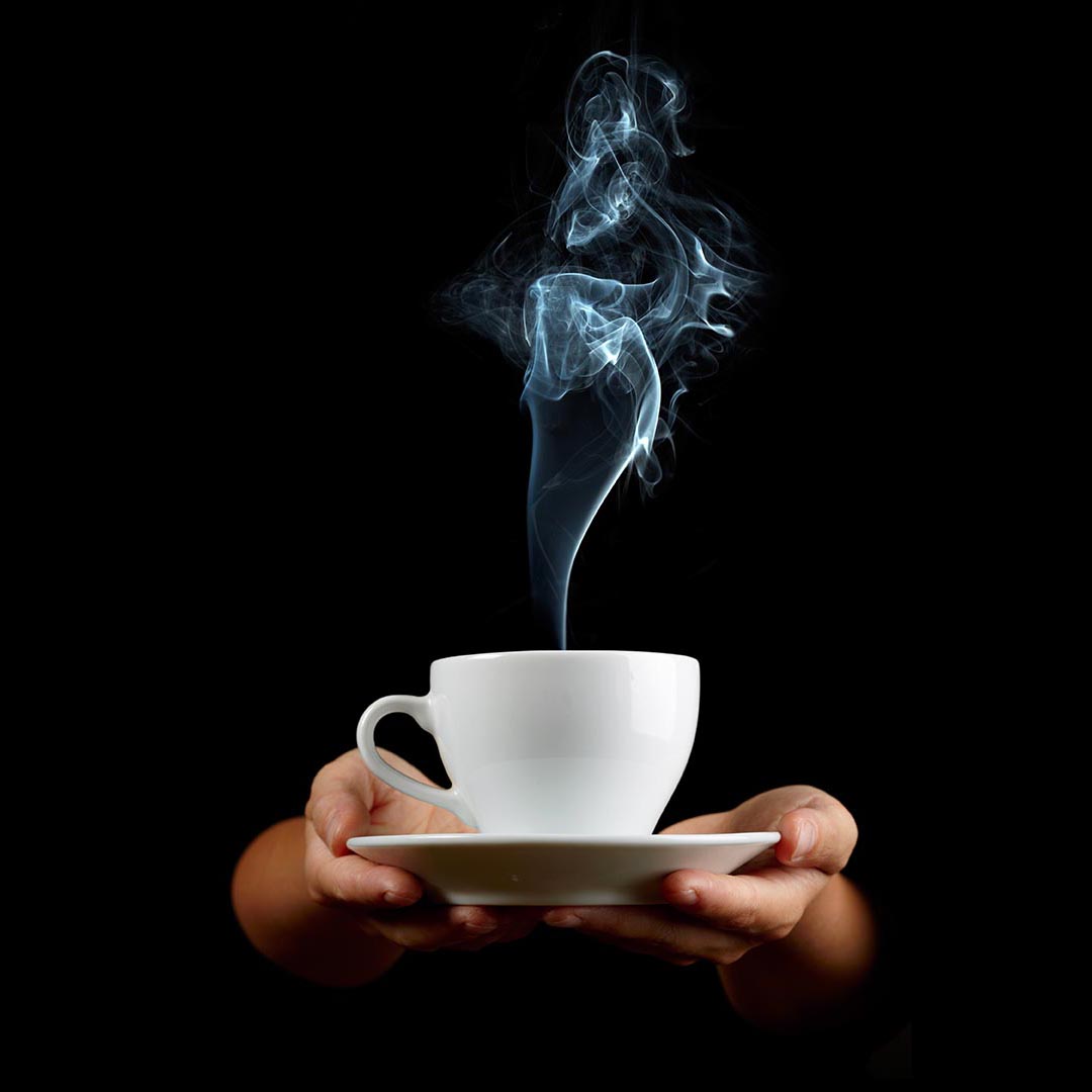 Cup of coffee in the women's hand on black background